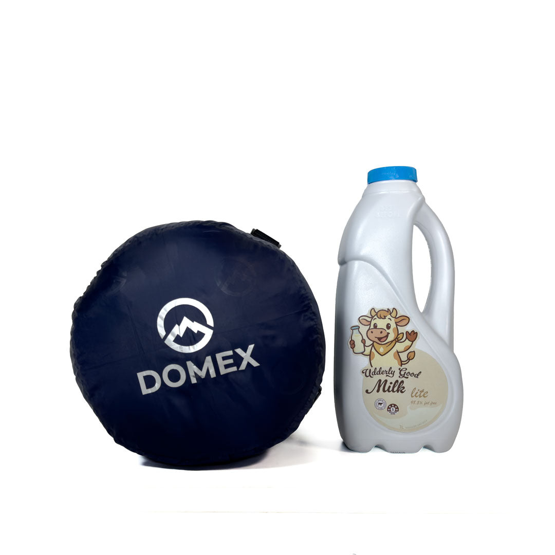 Logo end of compression sack for Domex Wanderer 300 - 2-season down bag shown next to 1 litre bottle of milk for scale